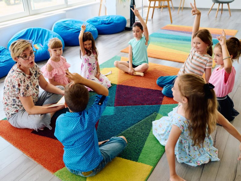 Teacher,Leading,Circle,Time,With,Young,Children,In,Colorful,Classroom
